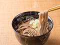 江戸時代には定着した日本の風習であり、蕎麦は他の麺類よりも切れやすいことから一年の苦労や厄災をさっぱり断ち切って新年を迎えるという説。そばは細く長く伸びるので、寿命を延ばし、家運を伸ばすという願いを込めた説。昔博多の寺で、年を越せない町人に「世直しそば」と称してそば餅をふるまったところ、翌年から運が向いてきたので、「運そば」と呼ばれて大晦日に食べるようになったという説。なにかしら意味を込めて多くの人が年越しそばを食べて、新しい年へ仕切り直しをするようです。給食委託サービス会社のラフトでは、無事1年を終える安堵と新年への期待で厨房は温かくも忙しい給食サービスの一日となります。